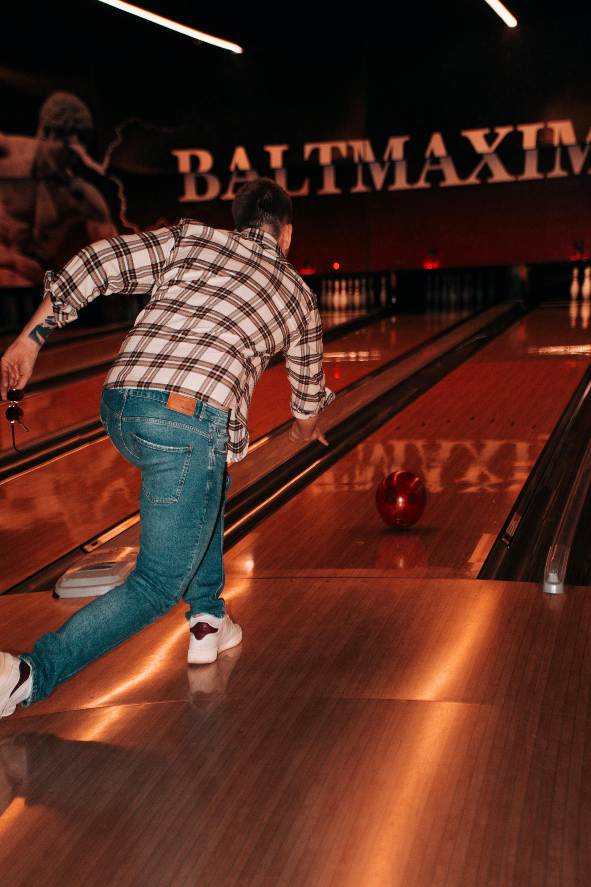 Rückansicht eines Mannes, der eine Kugel in einer Bowlingbahn wirft | Quelle: Pexels