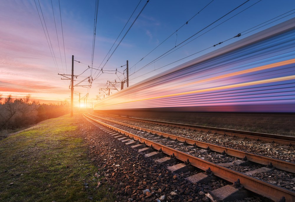 Hochgeschwindigkeitszug in Bewegung auf der Schiene bei Sonnenuntergang. I Quelle: Shutterstock