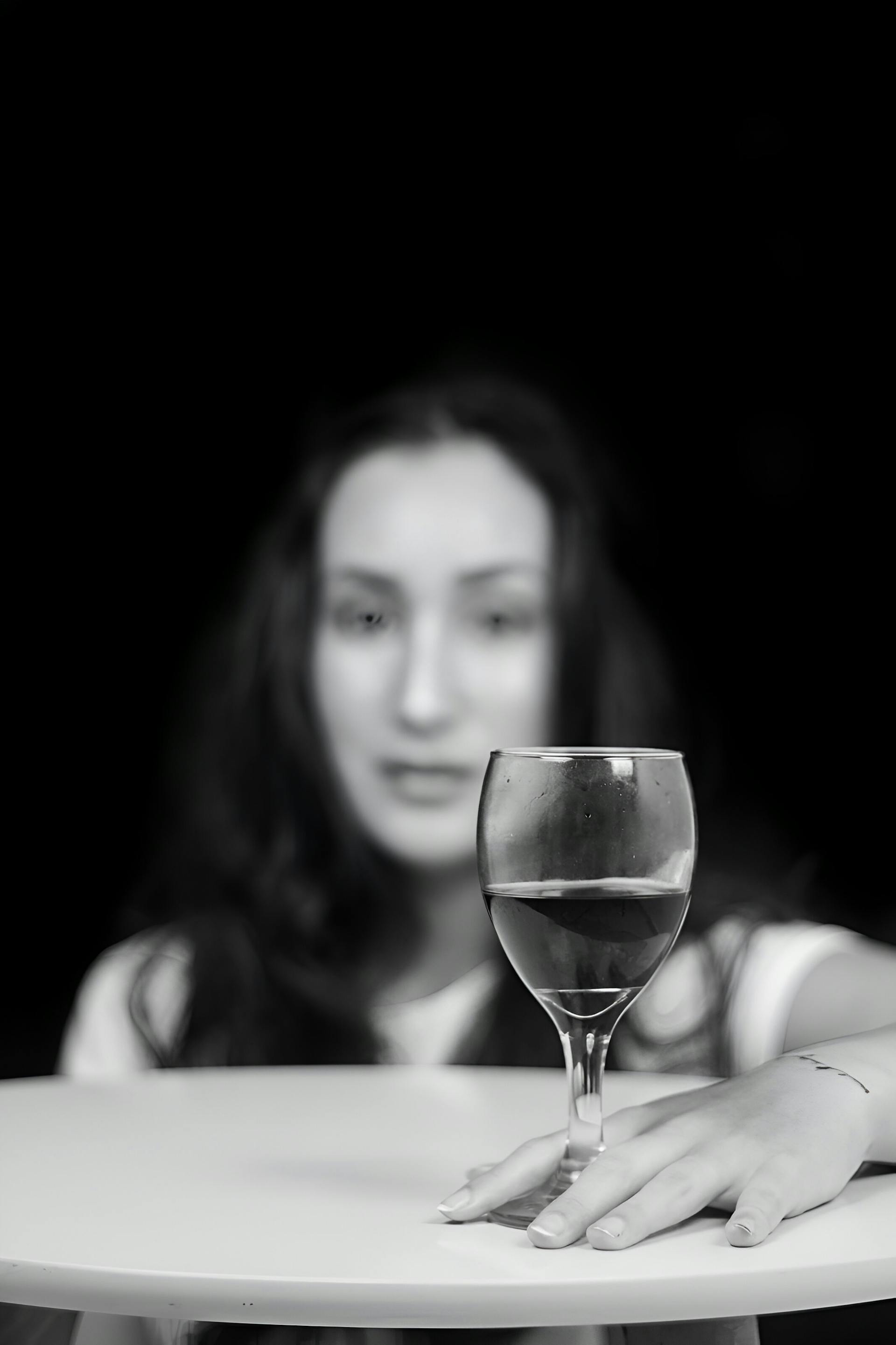 Graustufenbild einer Frau, die mit einem Glas Wein an einem Tisch sitzt | Quelle: Pexels