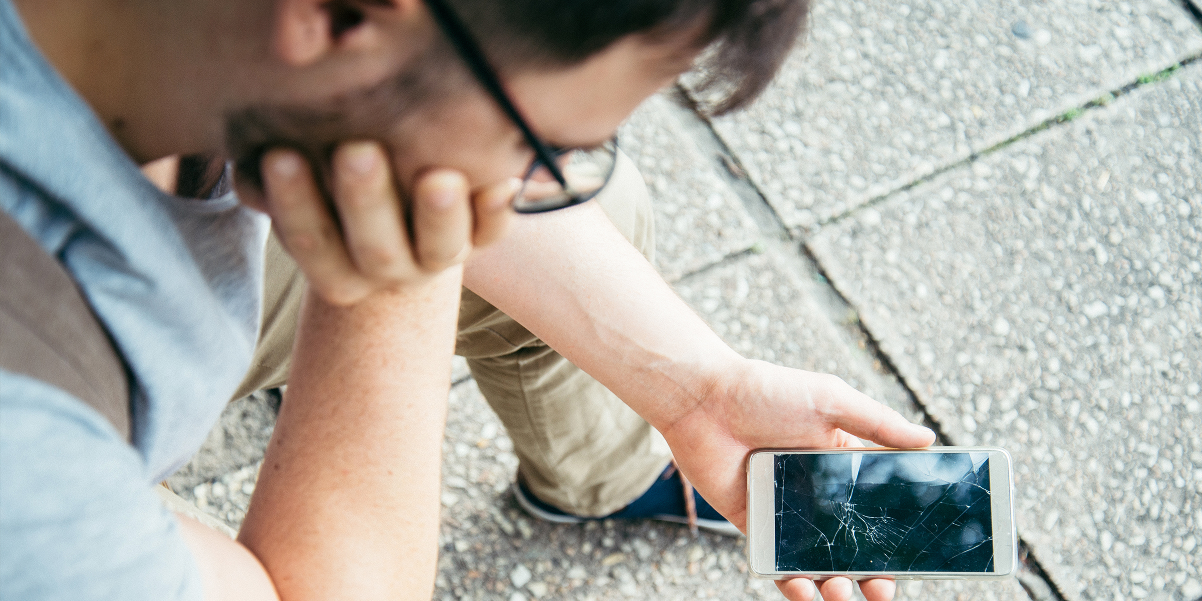 Ein Mann schaut auf ein kaputtes Telefon | Quelle: Shutterstock