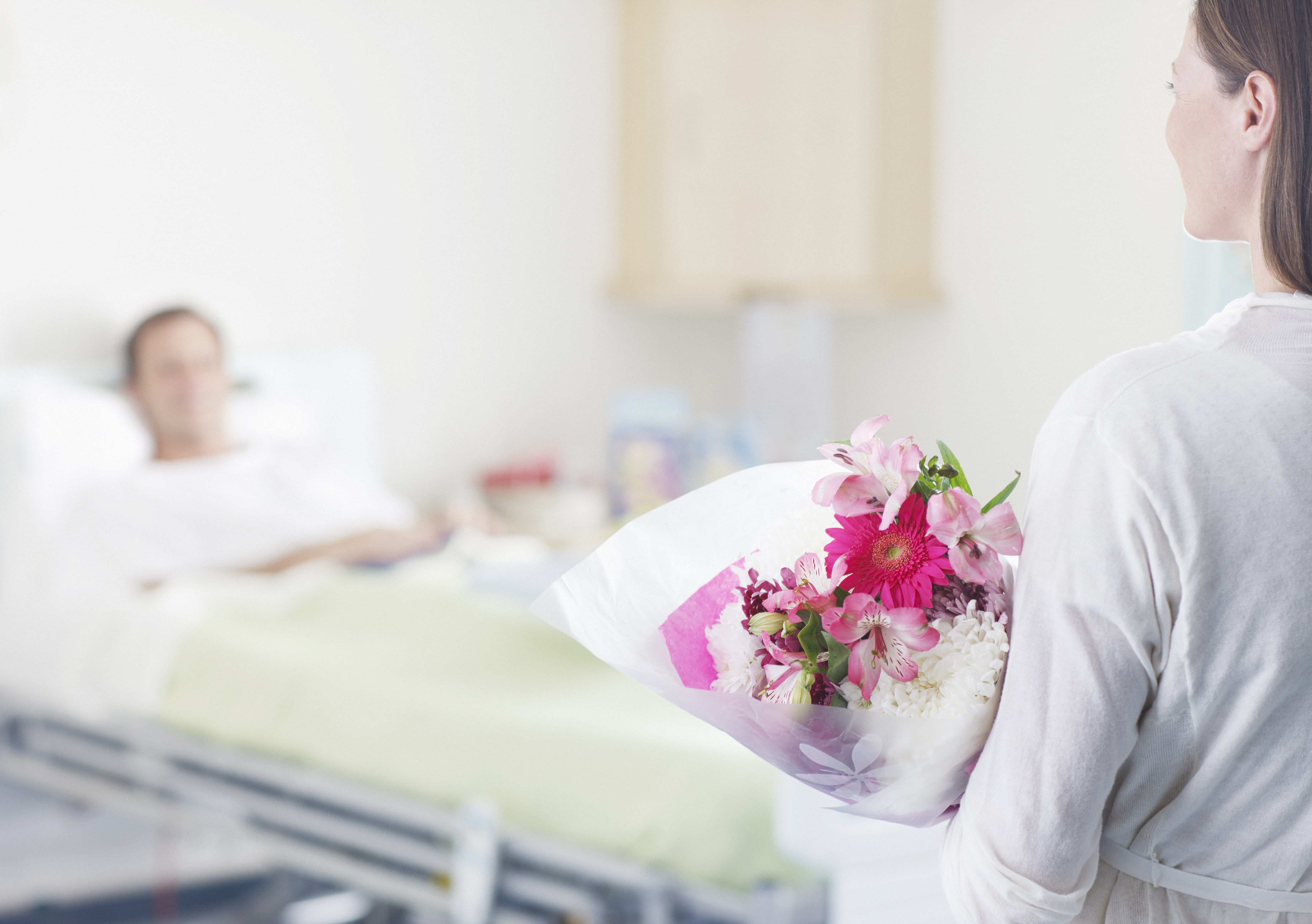 Eine Frau, die einem Mann in einem Krankenhaus Blumen bringt | Quelle: Getty Images