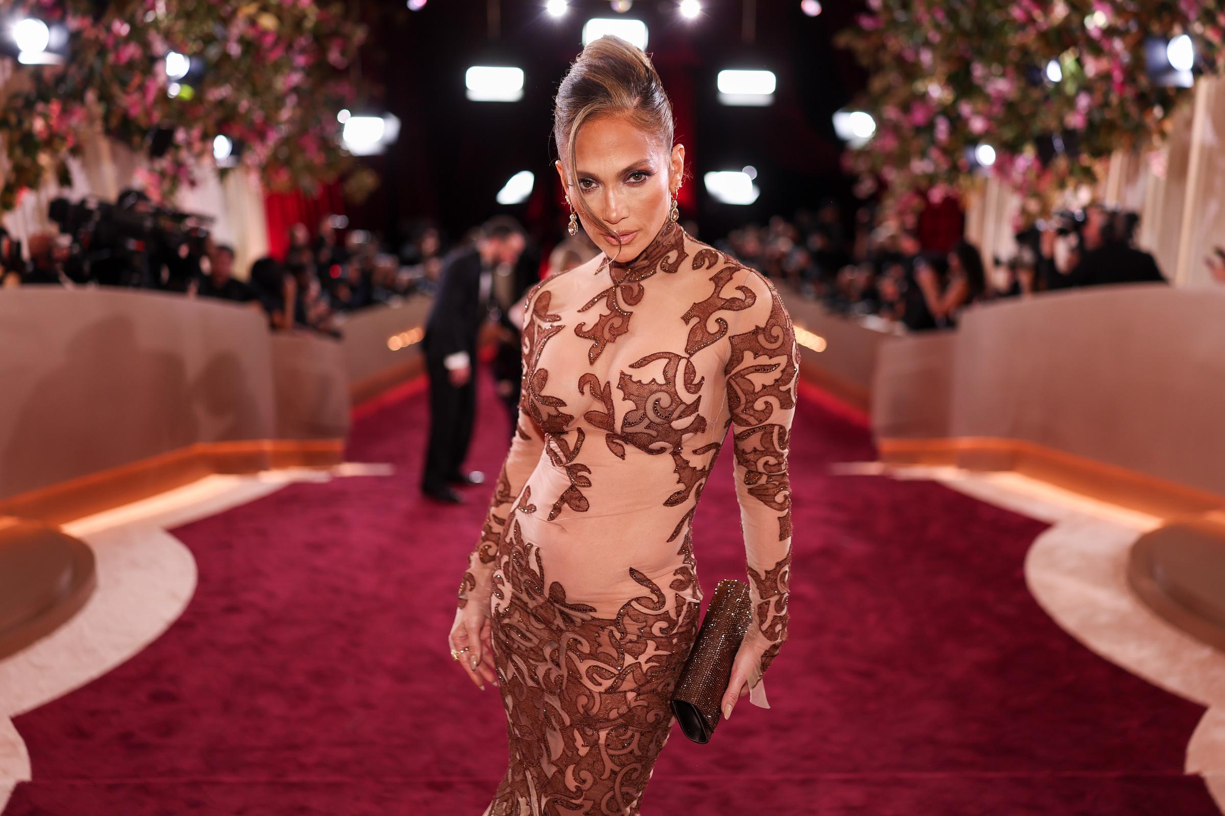 Jennifer Lopez posiert bei den Golden Globes 2026 auf dem roten Teppich in einem hochgeschlossenen, durchsichtigen, bestickten Abendkleid | Quelle: Getty Images