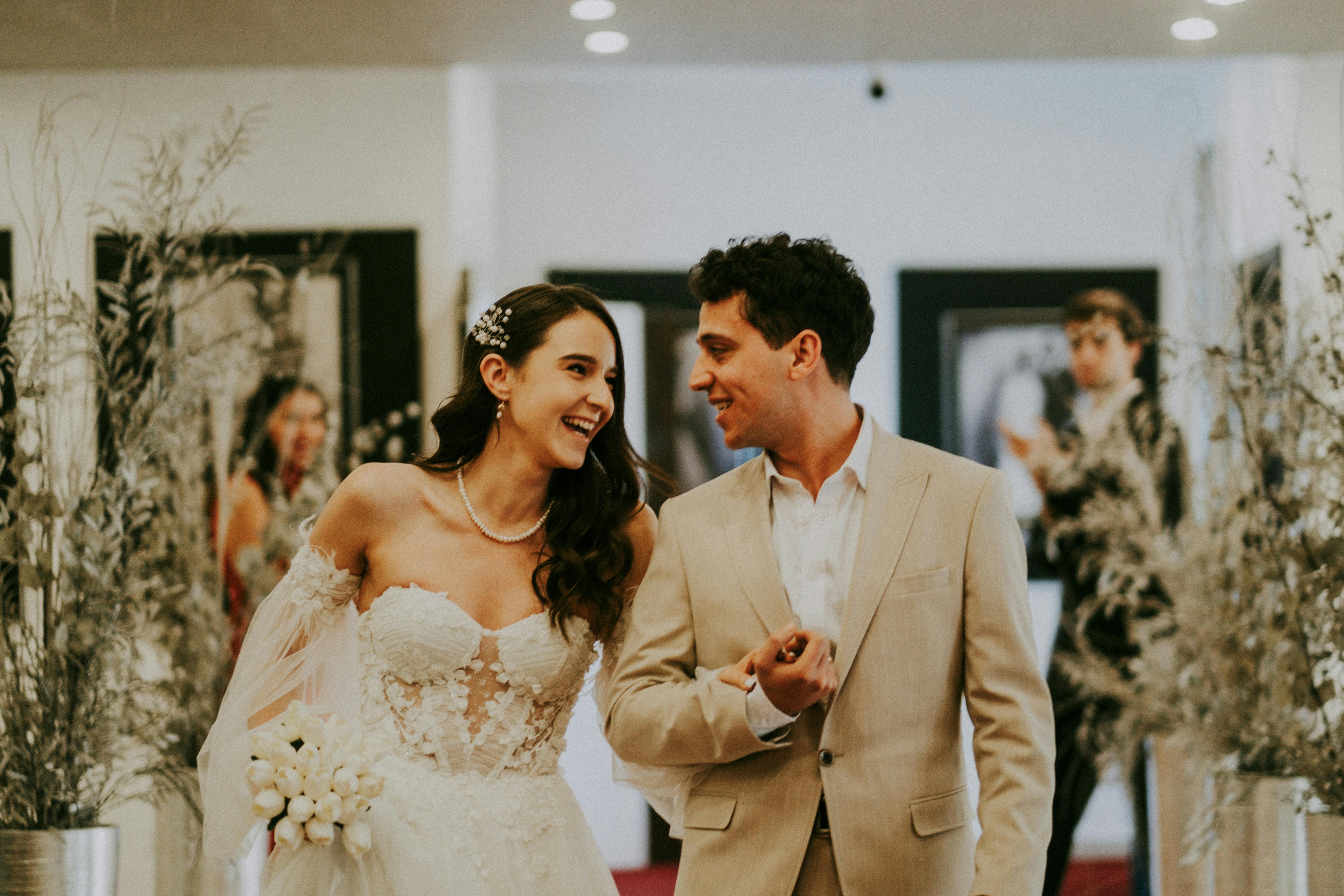 Braut und Bräutigam gehen Arm in Arm und schauen sich an | Quelle: Pexels
