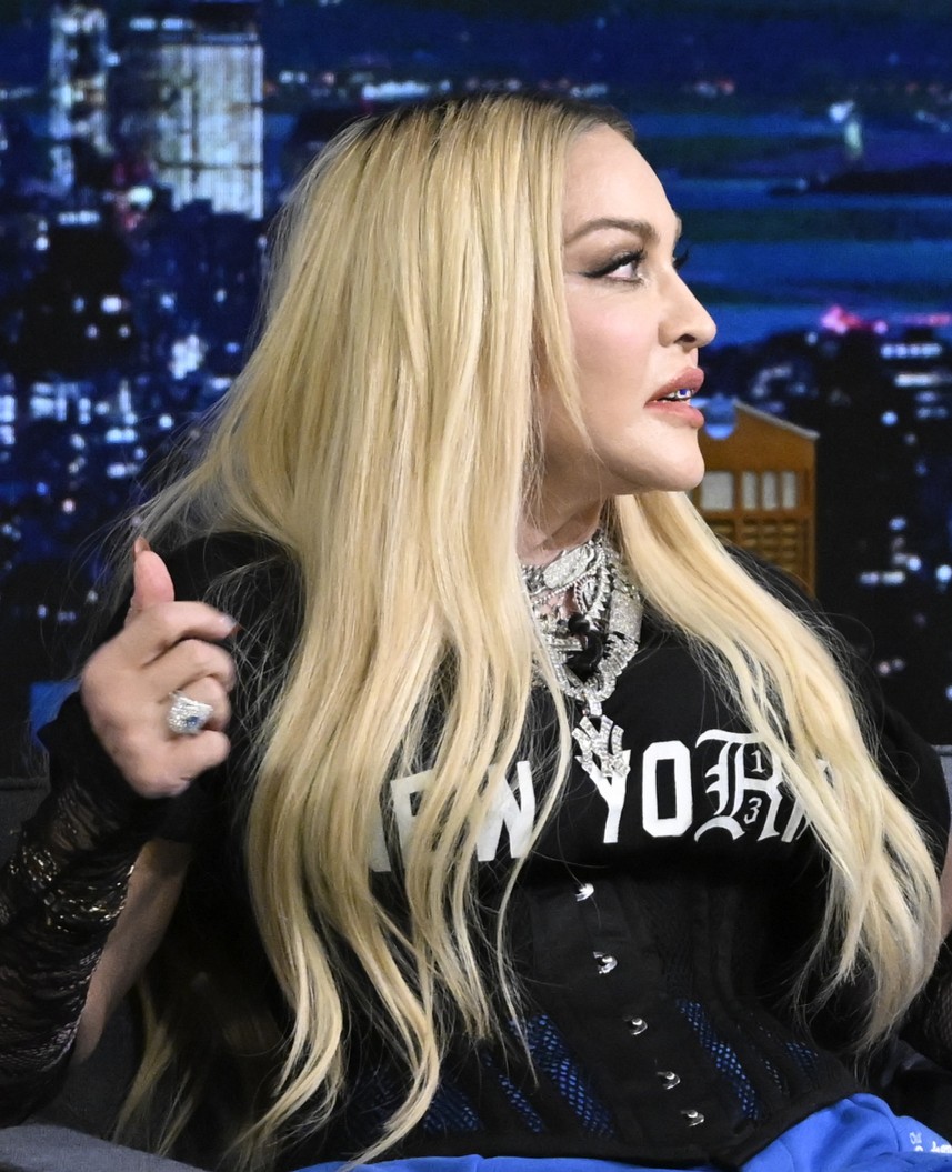 Madonna ist bei einem Fernsehauftritt im Profil zu sehen – mit langen blonden Haaren und einem schwarzen „New York“-Top, mehreren Halsketten und einem großen Statement-Ring. | Quelle: Chat GPT