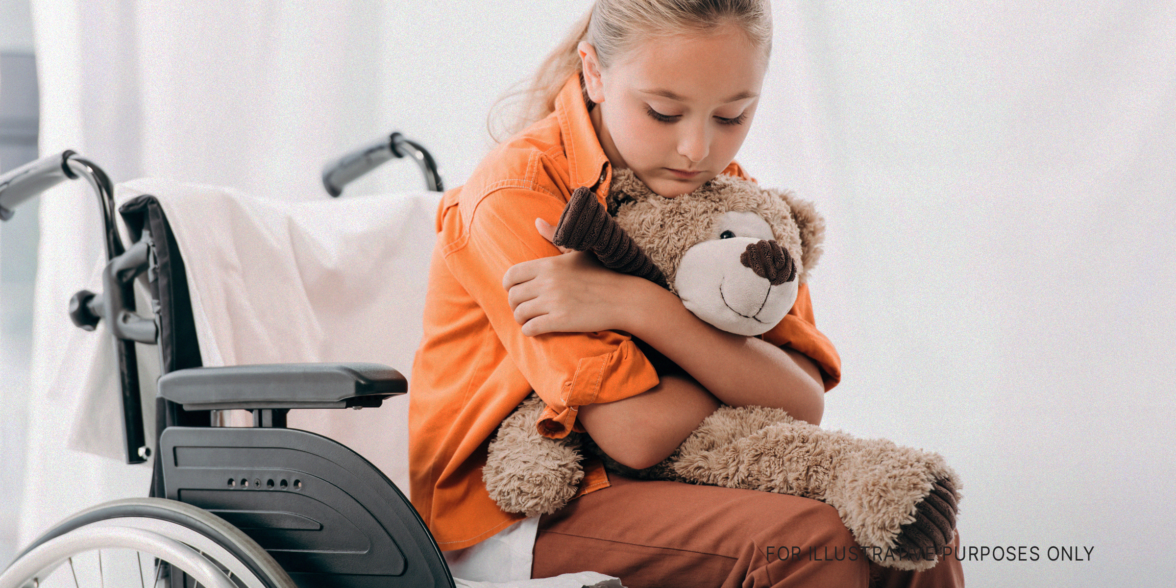 Kind, das mit einem Teddybär auf einem Rollstuhl sitzt | Quelle: Shutterstock