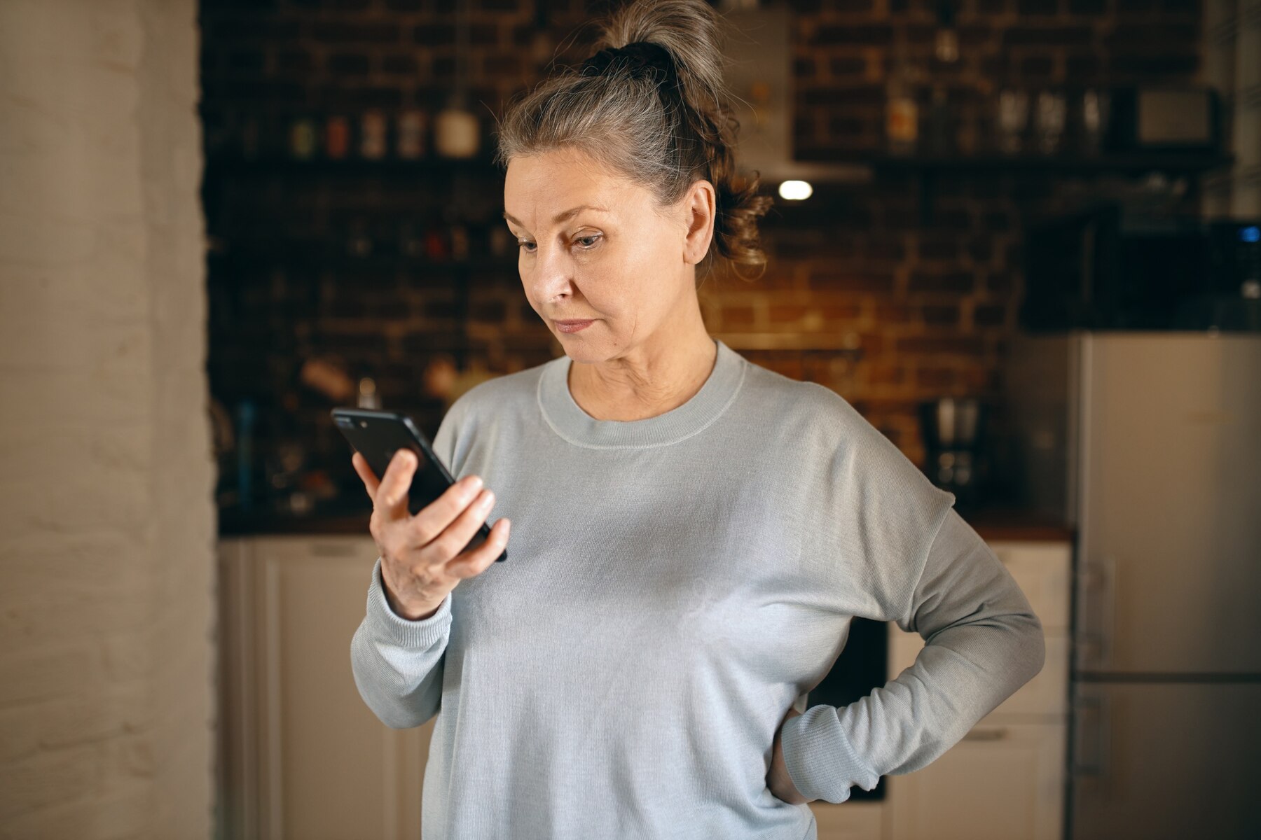 Eine wütende Frau mittleren Alters, die auf ihr Telefon schaut | Quelle: Freepik