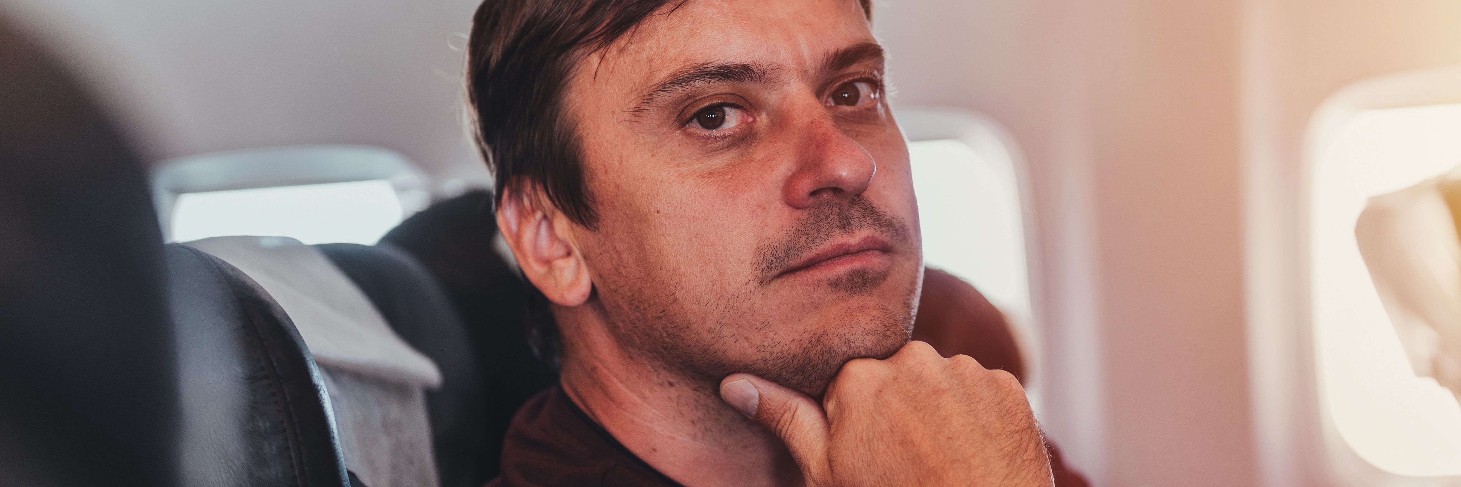 Nachdenklicher und schuldbewusster Mann in einem Flugzeug | Quelle: Shutterstock