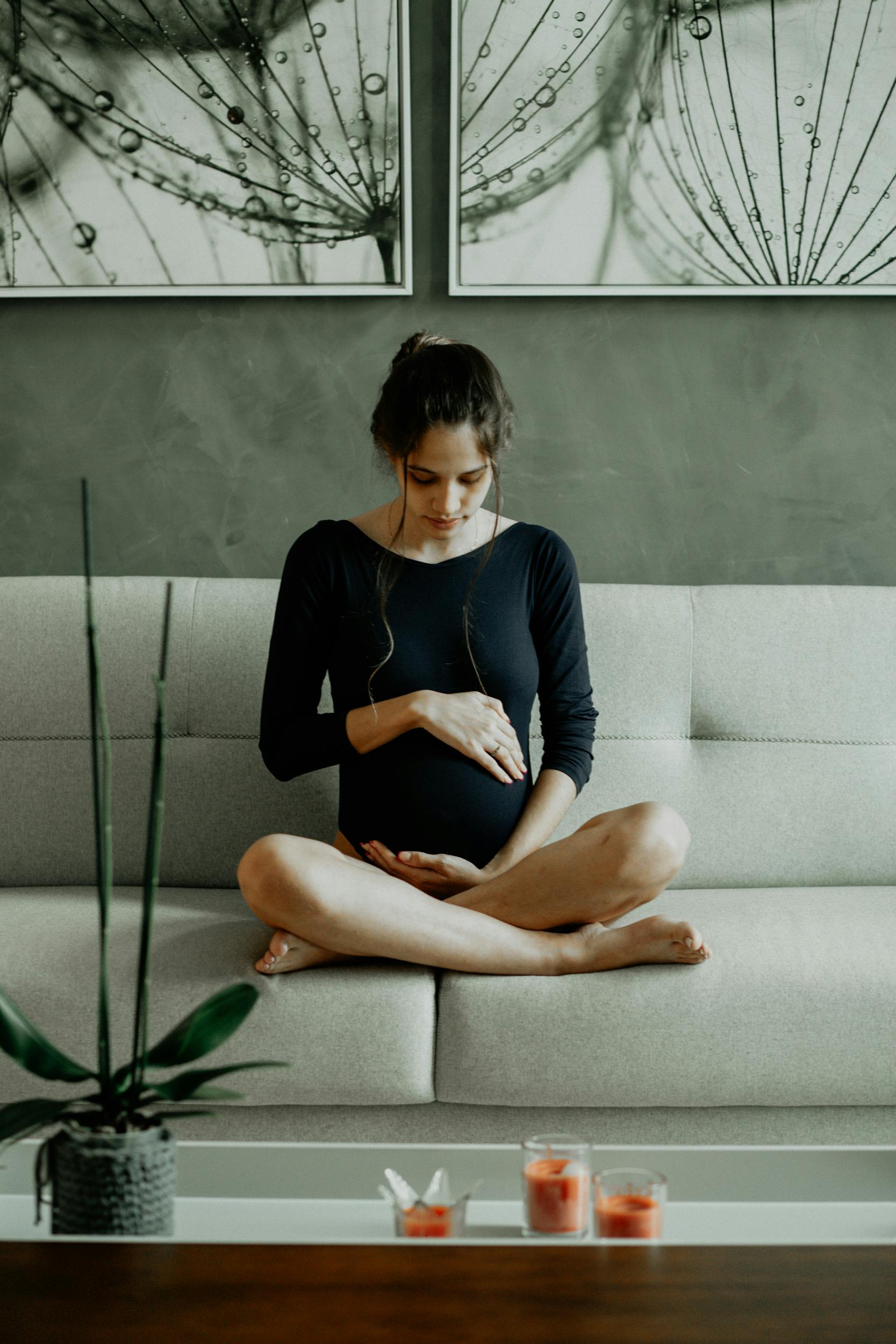 Eine schwangere Frau, die auf der Couch sitzt und ihren Bauch berührt | Quelle: Pexels