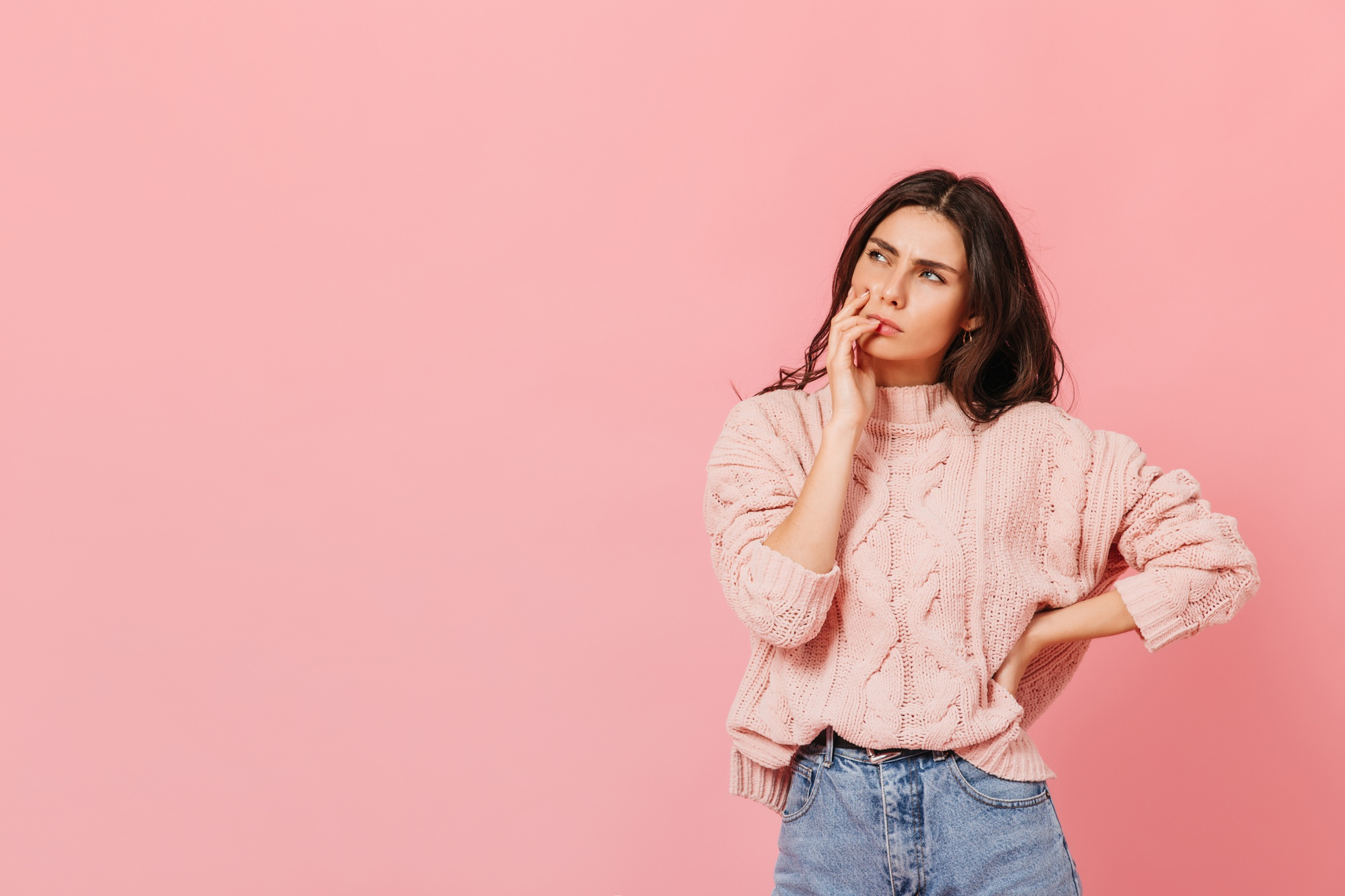 Eine Frau in einem rosa Pullover, die nachdenkt | Quelle: Freepik