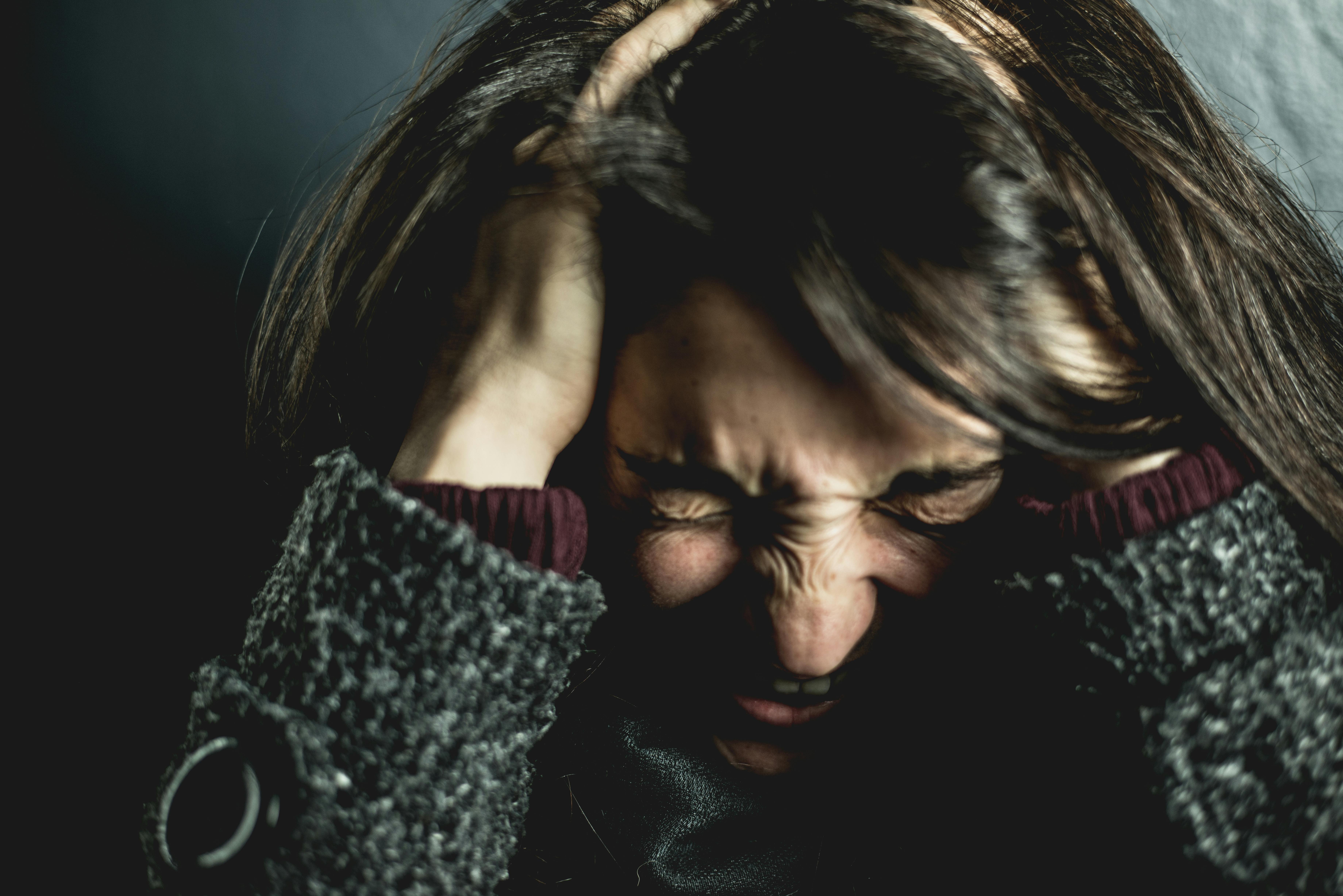 Eine Frau, die ihren Kopf mit den Händen bedeckt, während sie vor Frustration schreit | Quelle: Pexels