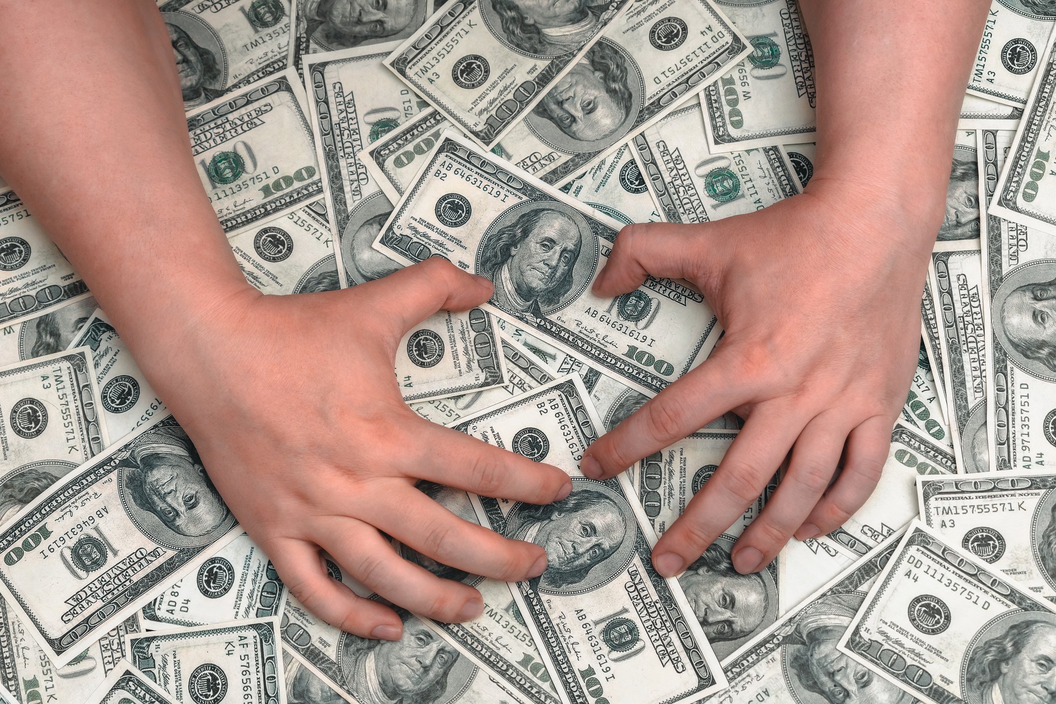 Ein Mann versucht, sich einen großen Haufen Geld von Hundert-Dollar-Scheinen zu nehmen | Quelle: Getty Images