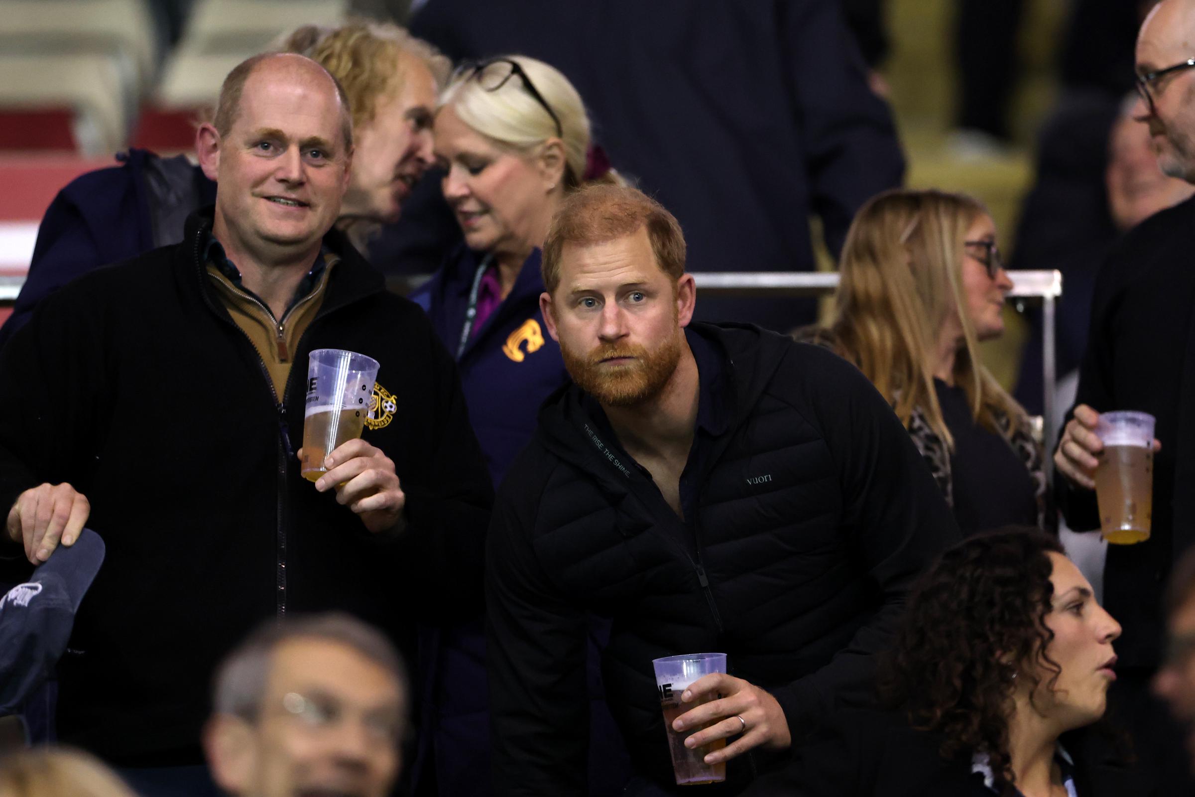 Prinz Harry schaut sich am 9. Oktober 2026 im Mattioli Woods Welford Road Stadium in Leicester, England, das Spiel der Leicester Tigers gegen Gloucester Rugby an. Er trägt eine schwarze Daunenjacke, hält ein Getränk in der Hand und gestikuliert, während er das Spiel verfolgt. | Quelle: Getty Images