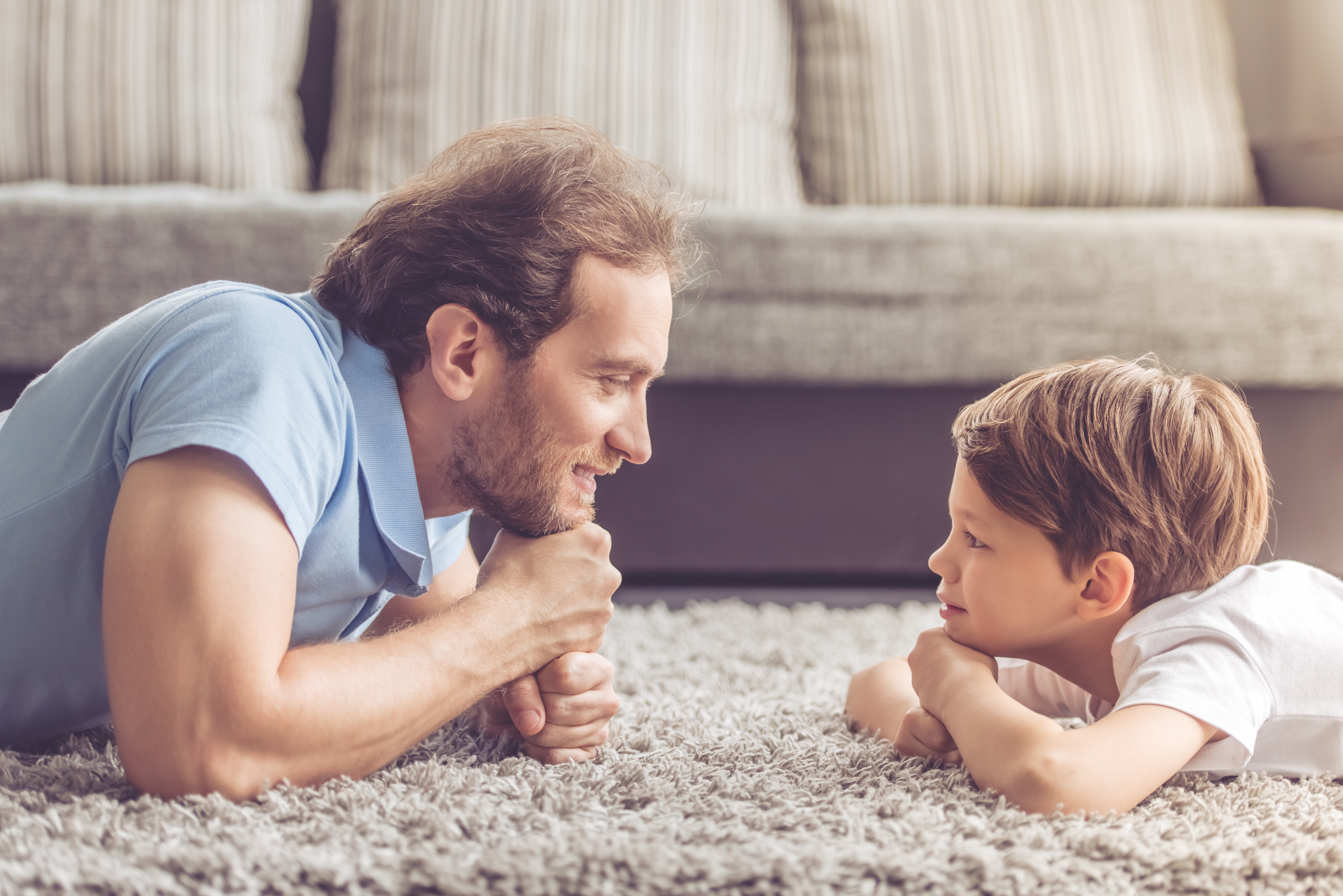 Seitenansicht eines Vaters und seines Sohnes, die einander betrachten und lächeln. | Quelle: Shutterstock
