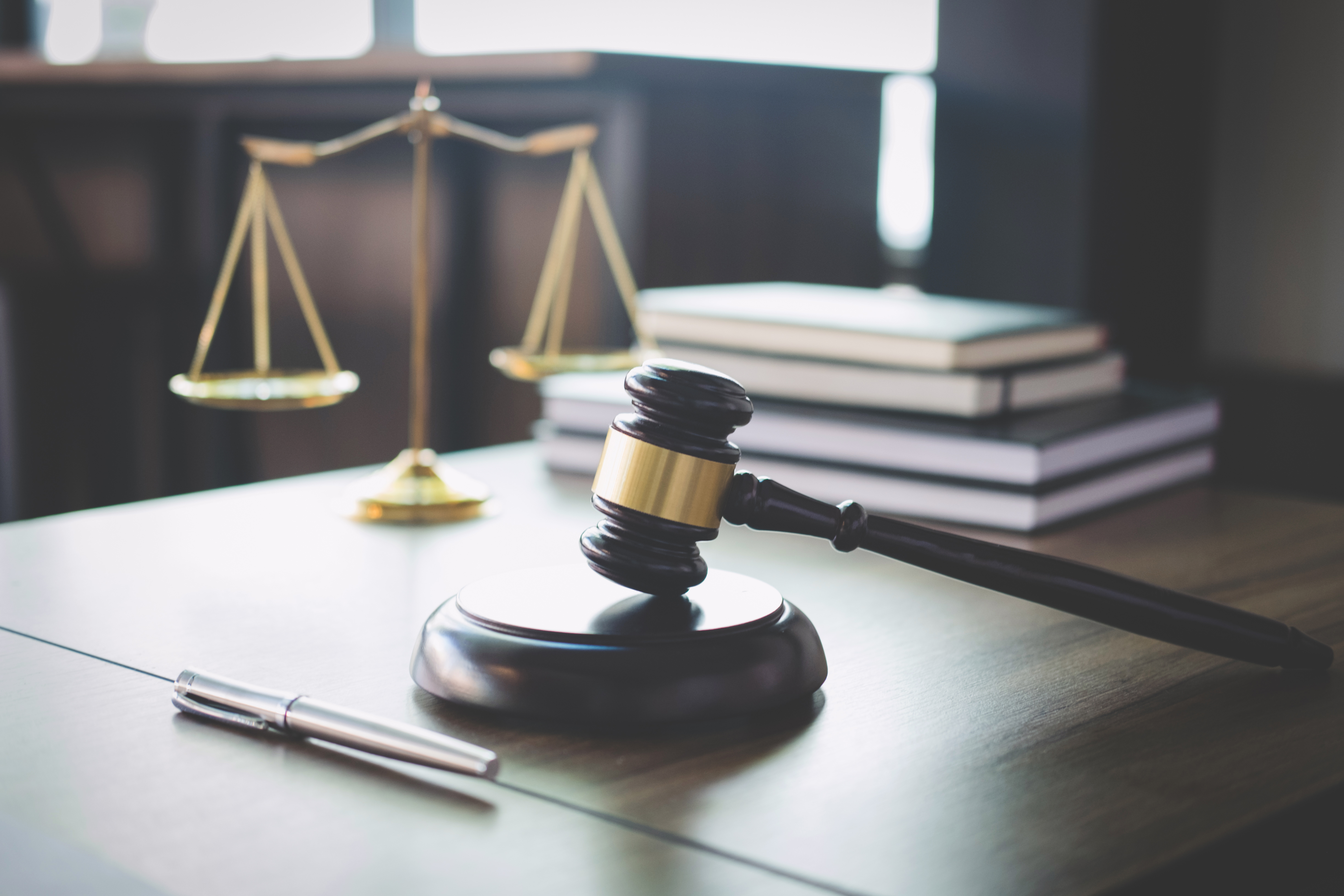 Die Waage der Gerechtigkeit und der Hammer liegen auf einem Holztisch in einem Anwaltsbüro | Quelle: Getty Images