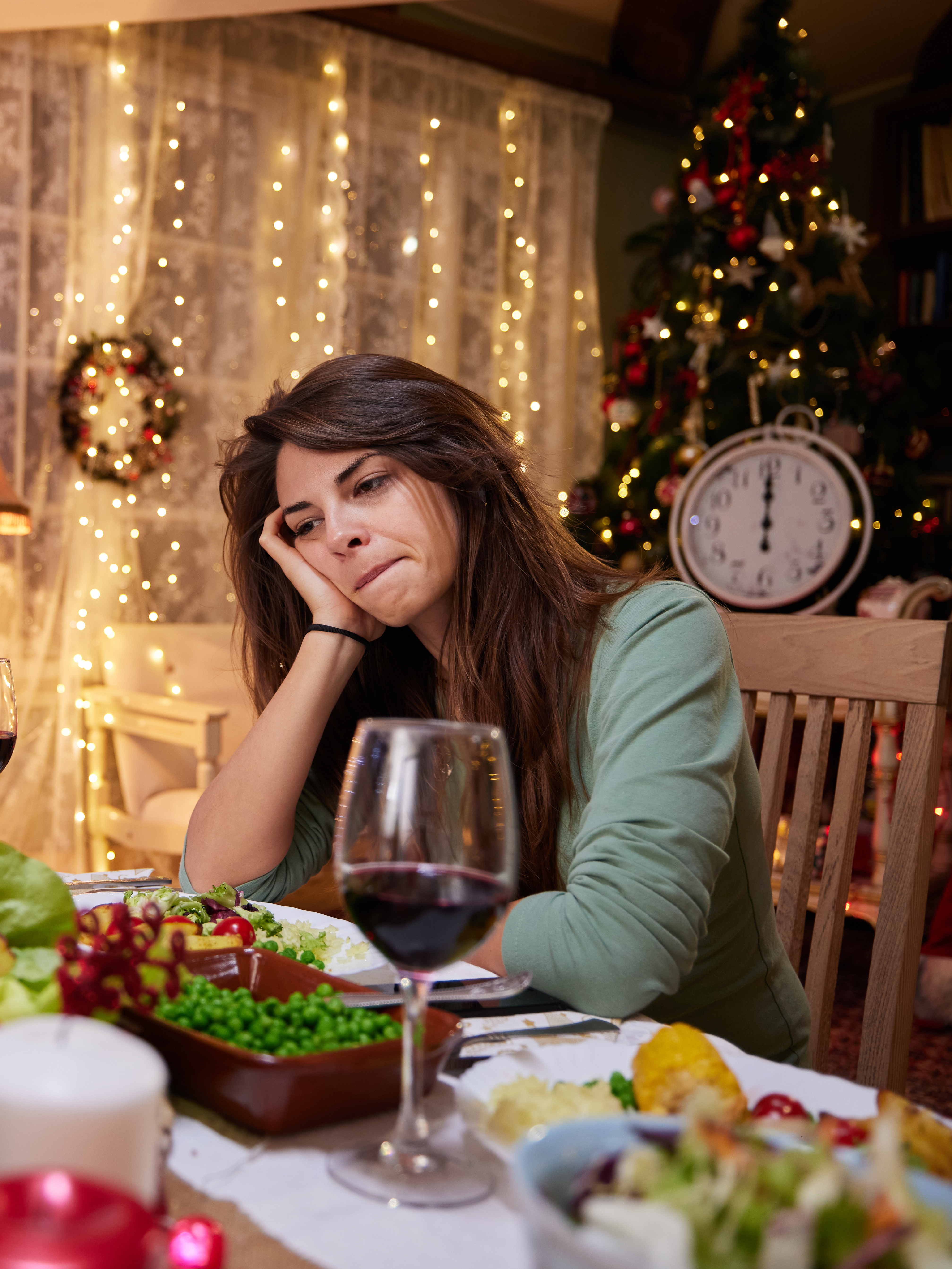 Eine traurige Frau, die an Heiligabend allein am Esstisch sitzt | Quelle: Getty Images