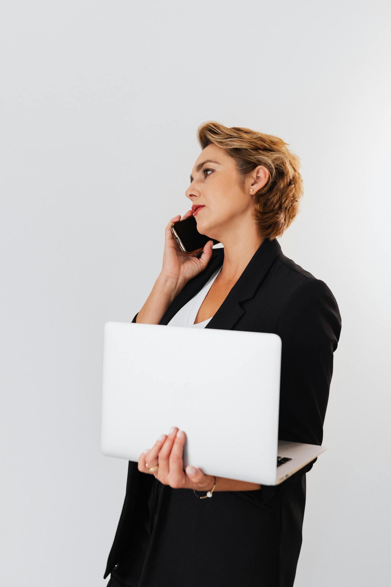 Eine Frau telefoniert mit einem Laptop in der Hand | Quelle: Pexels